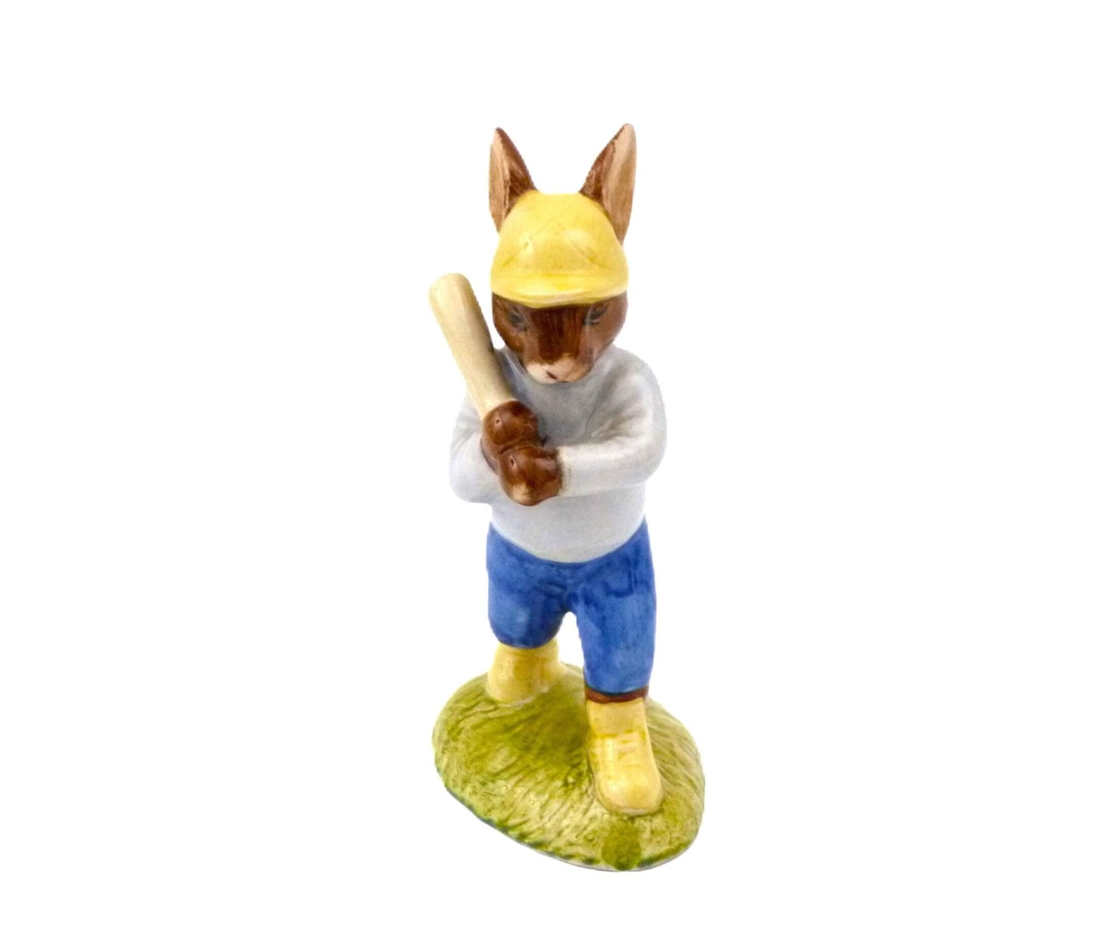 A baseball bunny wearing a yellow cap and shoes, with blue trousers and a white top. His baseball bat is ready resting on his shoulder.