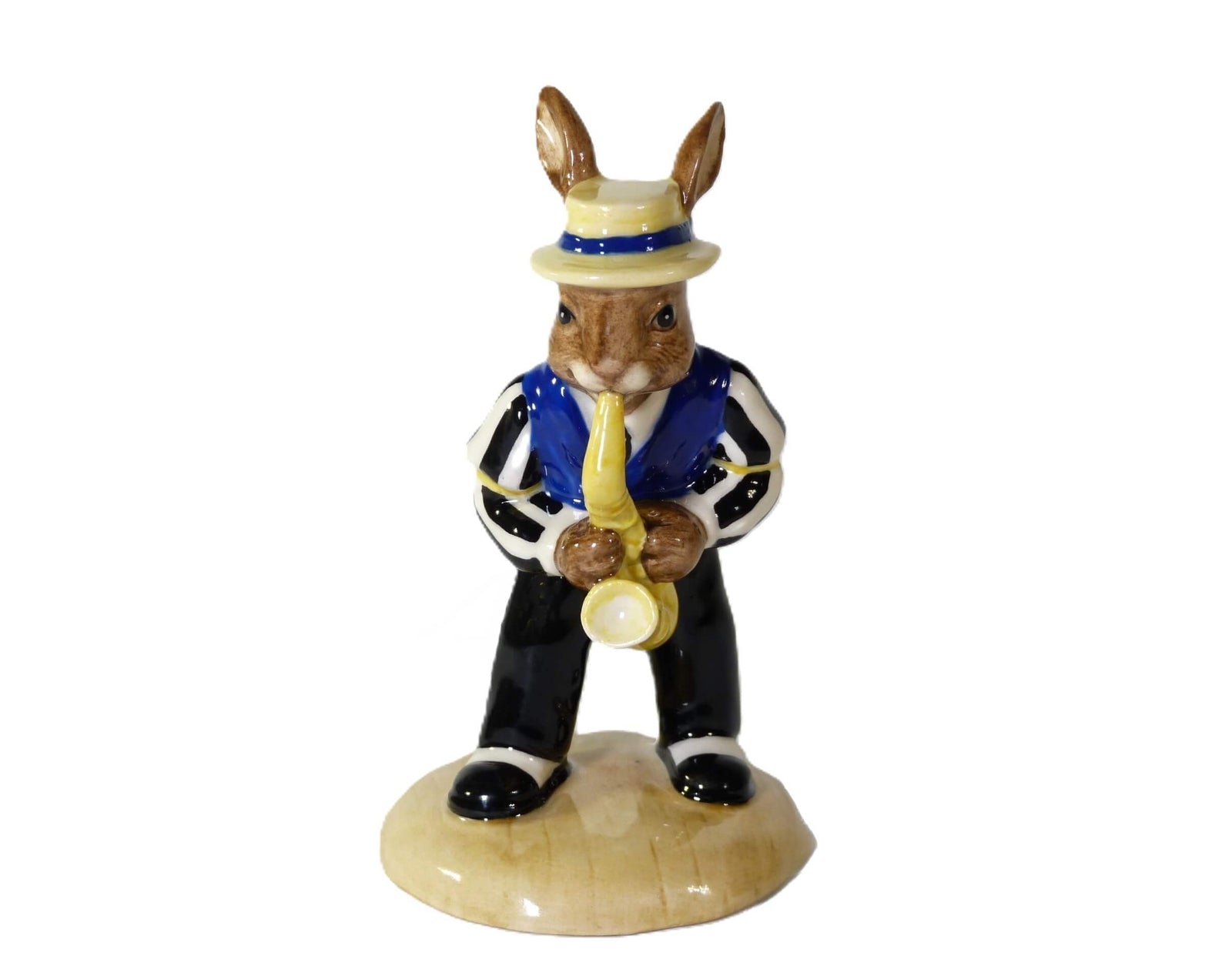 The Bunnykin is wearing black pants, a black and white striped shirt, a blue vest and a straw boater hat. He is playing his saxaphone.